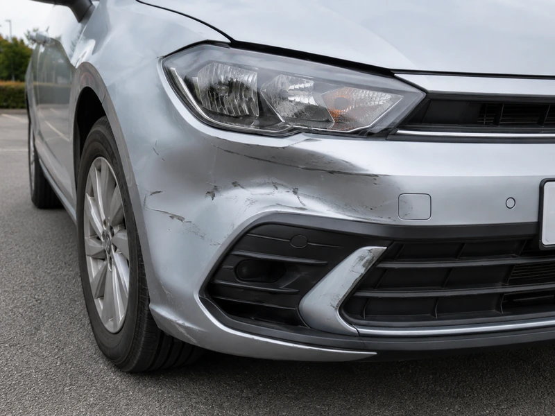 Example close-up photograph of a damaged car wing showing a dent and paint damage